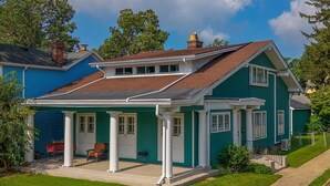 A two-story house with a green exterior, white trim, and a covered front porch with columns. - Your Summer HQ!  Ditch the Hotel Rooms! Sleeps 11.   Pet-Friendly! (Dayton)