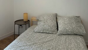 A bedroom with a bed, a small bedside table, a lamp, and a wall art of a fruit. - Tastefully renovated apartment close to sea, town and amenities! (Toulon)