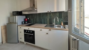A modern kitchen with white cabinets, a stainless steel sink, a built-in oven, and a microwave. - Tastefully renovated apartment close to sea, town and amenities! (Toulon)