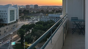 A balcony with a view of a cityscape during sunset, including buildings and a road. - Tastefully renovated apartment close to sea, town and amenities! (Toulon)