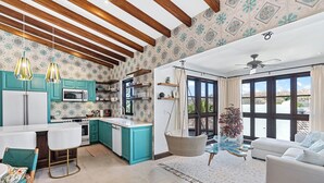 A modern kitchen with teal cabinets, a white countertop, and a hanging light fixture. - Trendy Condo with Modern Decor, Stunning Ocean Views, and Exclusive Beach Club Access (Las Catalinas)