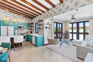 Una cocina moderna con armarios color turquesa, encimera blanca y una lámpara colgante.