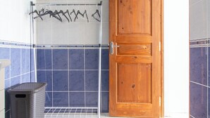 A bathroom with a wooden door, a towel rack, and a trash bin.