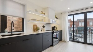 A modern kitchen with dark cabinetry, a large window, and a view of the city.