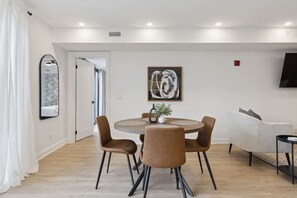 A modern dining area with a round table, four chairs, and a vase with plants. - Condo for 4 Overlooking Downtown Collingwood (Collingwood)
