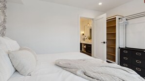 A bedroom with a bed, a wardrobe, and a bathroom visible through an open door.