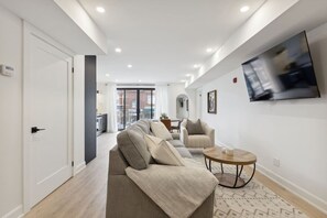 A modern living room with a sofa set, a coffee table, and a flat-screen TV mounted on the wall. - Condo for 4 Overlooking Downtown Collingwood (Collingwood)