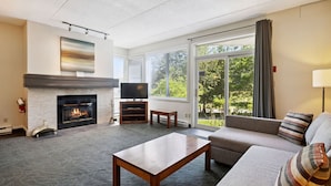 A modern living room with a fireplace, a flat-screen TV, a sofa, and a coffee table. - Ground-Floor Cachet Crossing, Steps to BM Village! (The Blue Mountains)