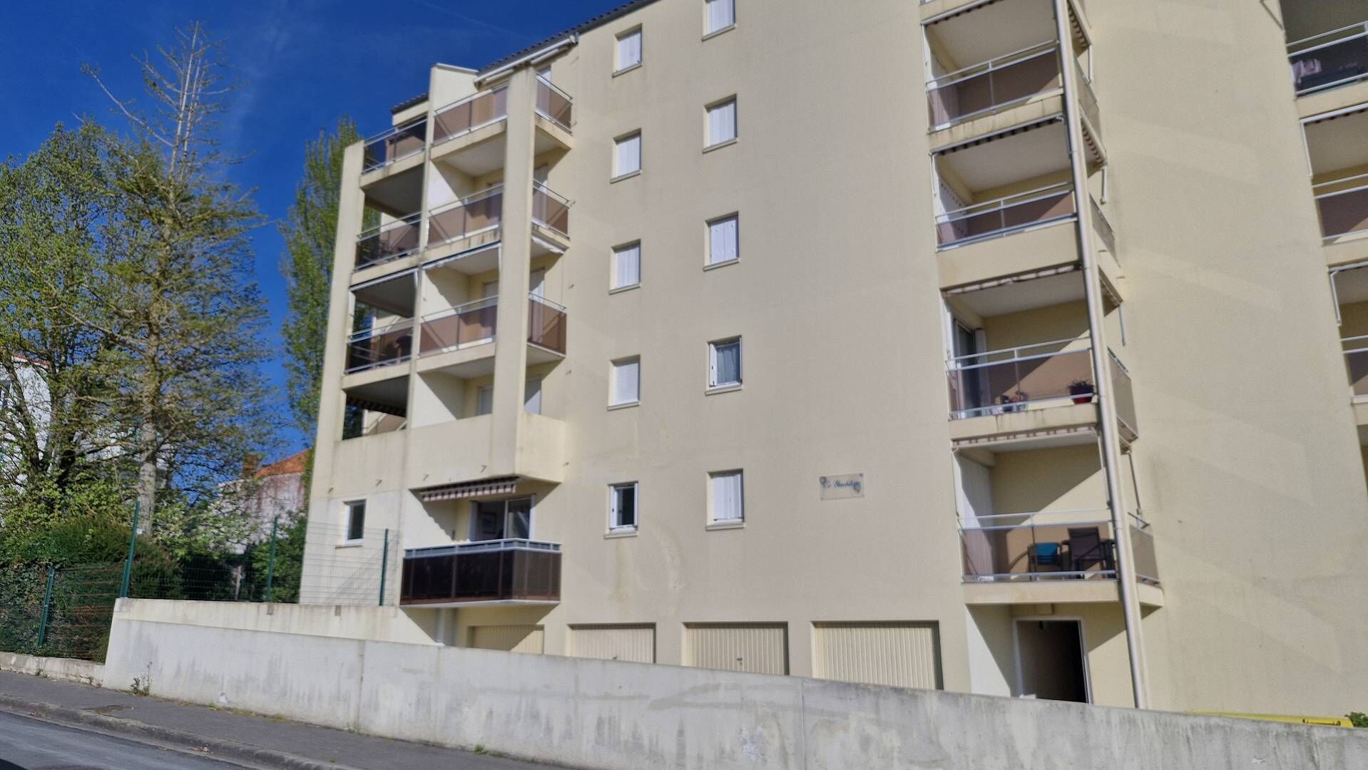 Un edificio residencial de varios pisos con balcones, base de hormigón y cielo despejado.