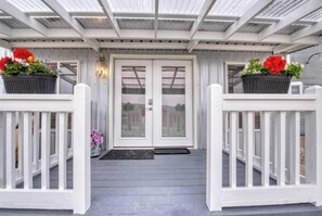Relax on the covered porch with a double door entrance, flanked by planters with vibrant flowers.