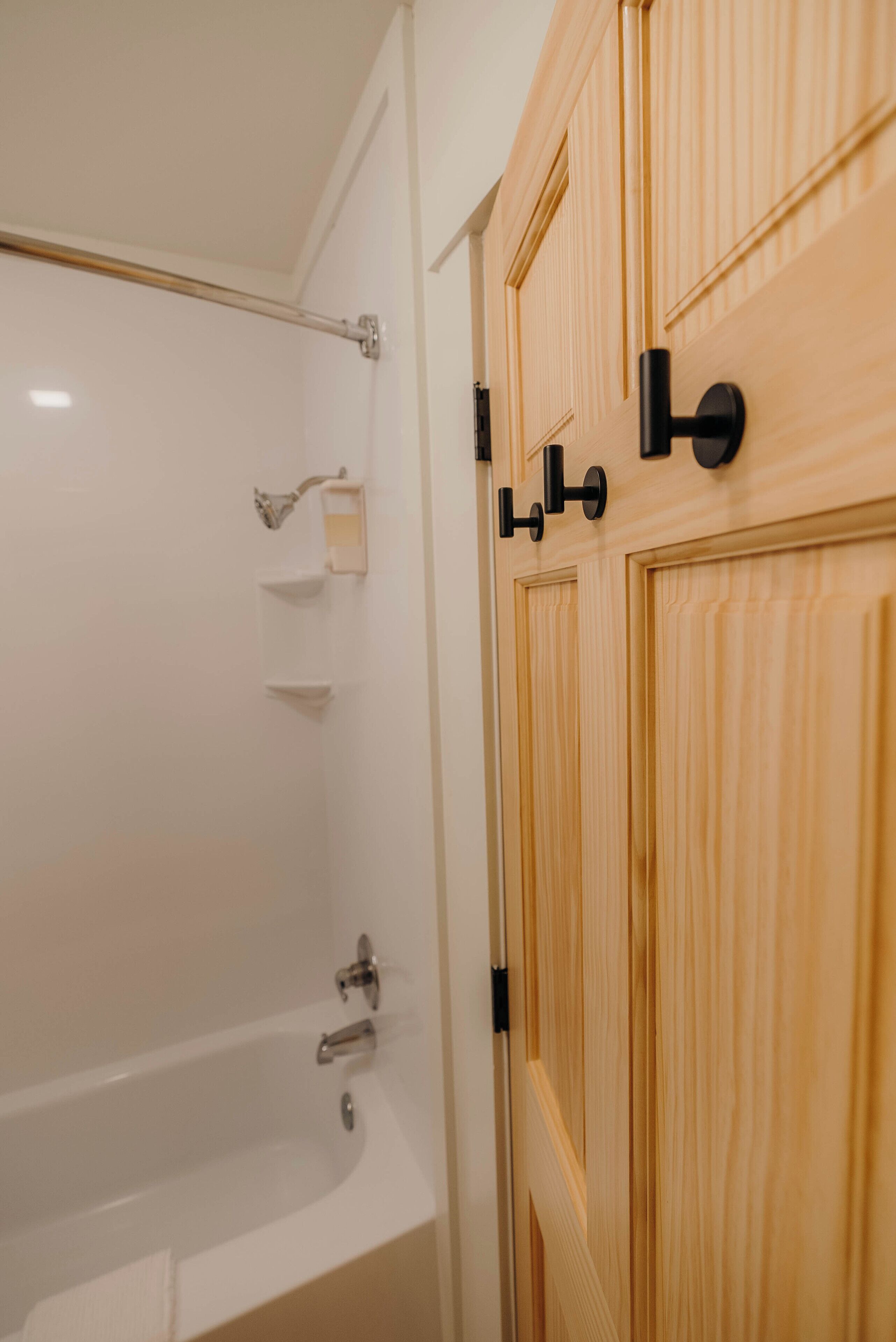 A bathroom with a bathtub, a wooden door, and a towel rack.