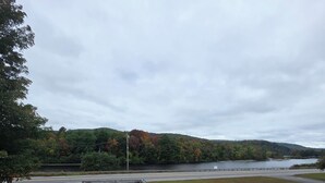 A wooden deck with a table, overlooking a body of water and a road. - Bingham Motor Inn (Bingham)