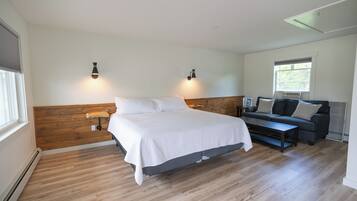 A bedroom with a bed, a wooden headboard, a sofa, and a window.