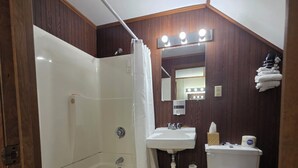 A bathroom with a bathtub, a sink, a toilet, and a mirror with lights.