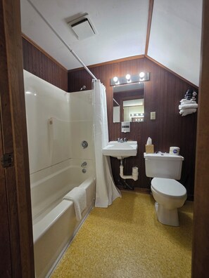 A bathroom with a bathtub, a sink, a toilet, and a mirror with lights.