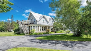 A two-story house with a prominent front porch, a staircase leading to the upper floor, and a well-maintained lawn.