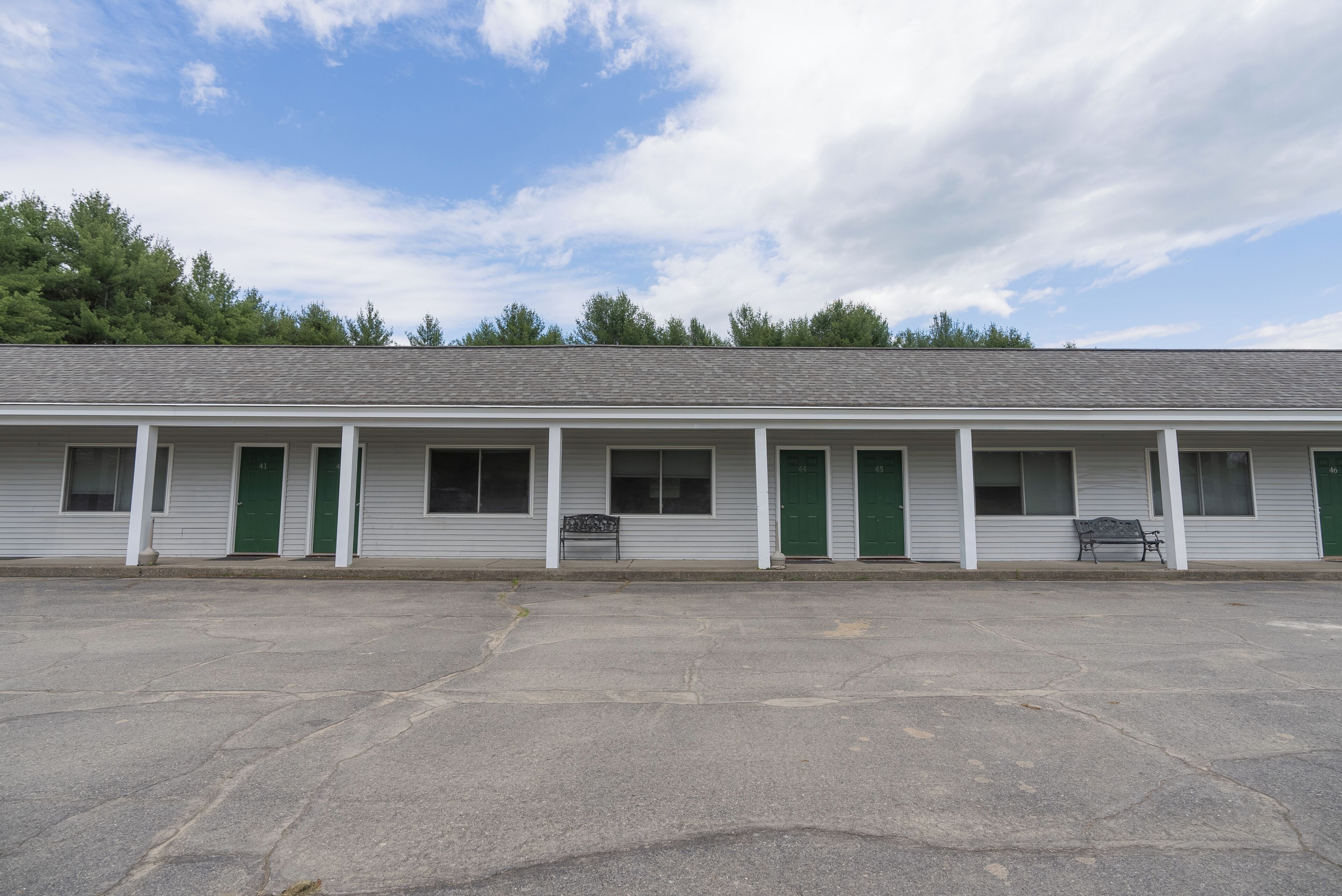 A motel with a row of rooms, each with a green door and windows.