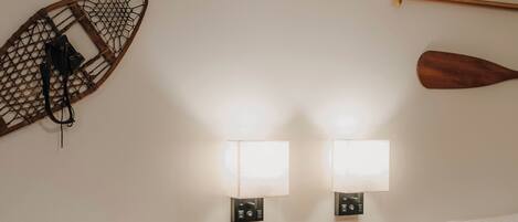 A hotel room with two beds, wooden headboards, a small wooden table, and wall-mounted lights.