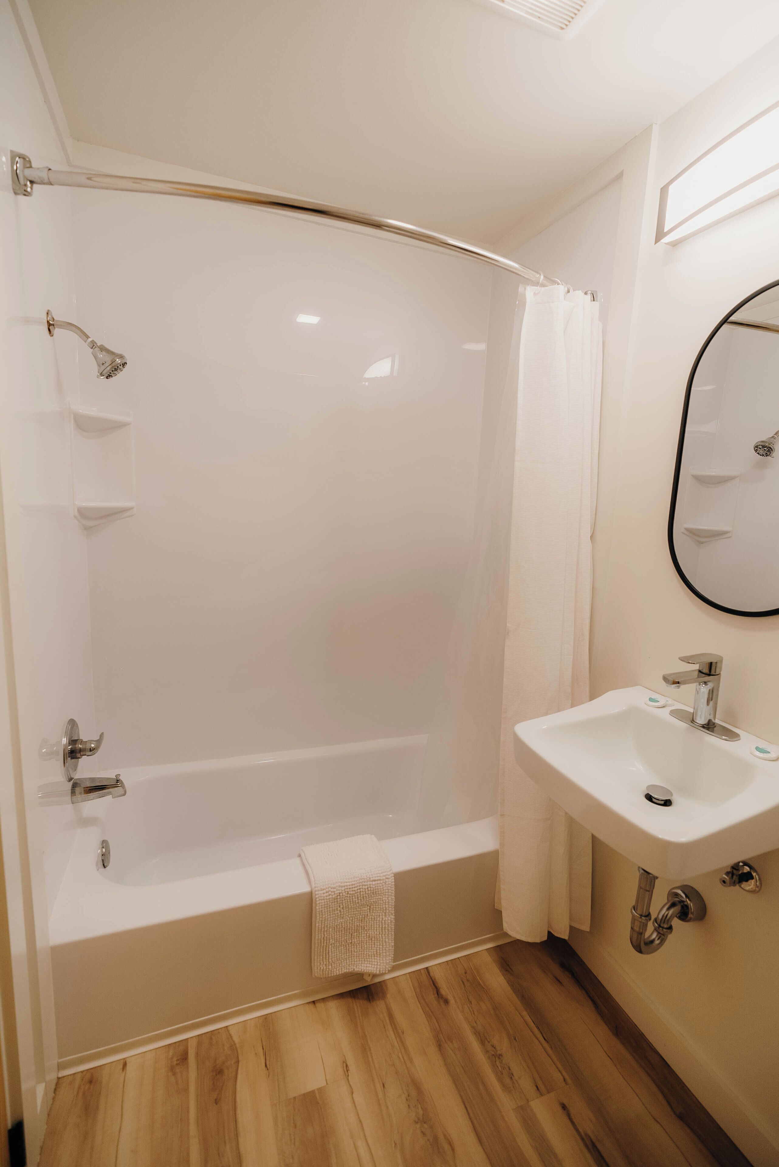 Un baño con bañera, ducha, lavamanos y espejo.