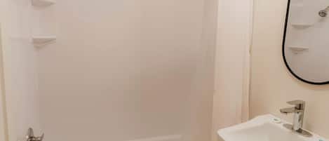 Un baño con bañera, ducha, lavamanos y espejo.