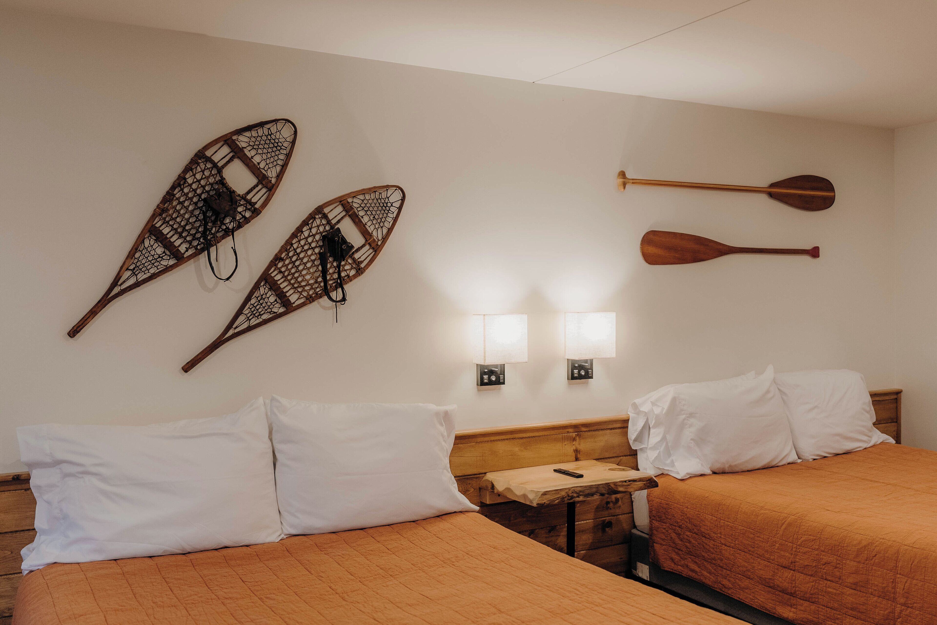 Ein Hotelzimmer mit zwei Betten, einem Nachttisch aus Holz und Wandleuchten.