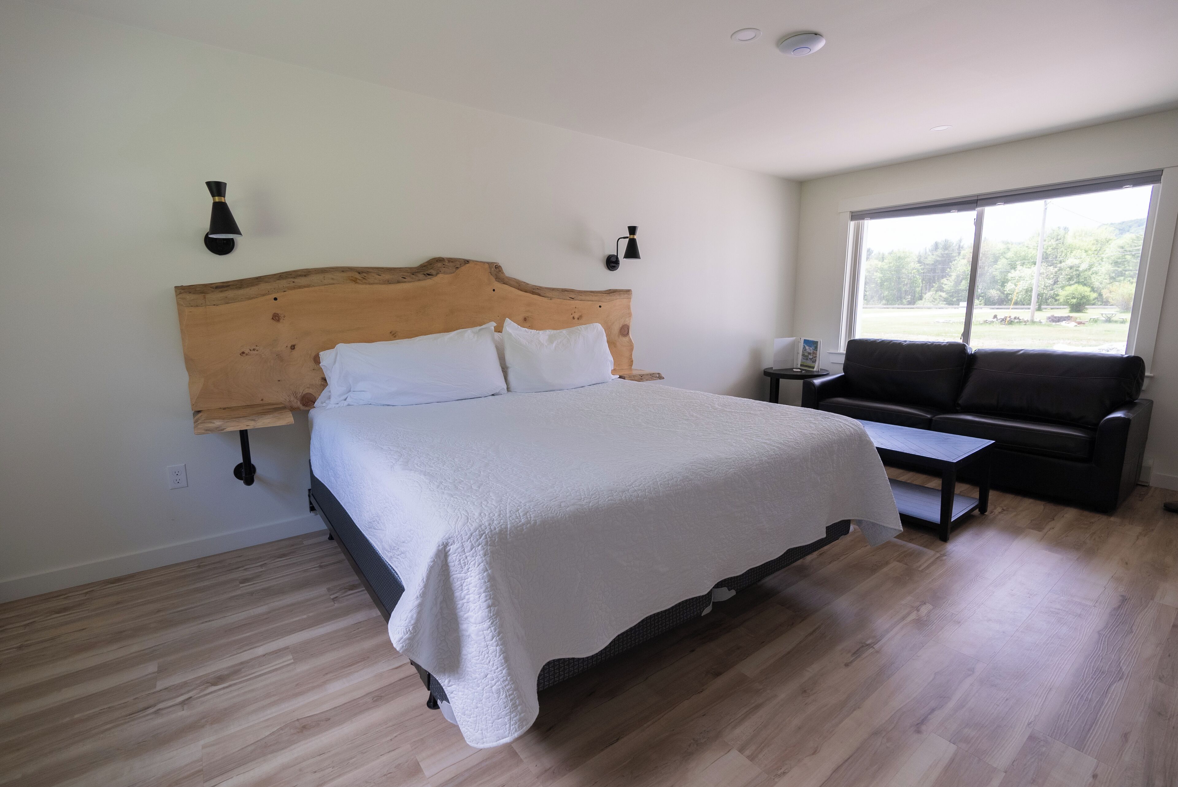 A bedroom with a wooden headboard bed, a small table, and a sofa.