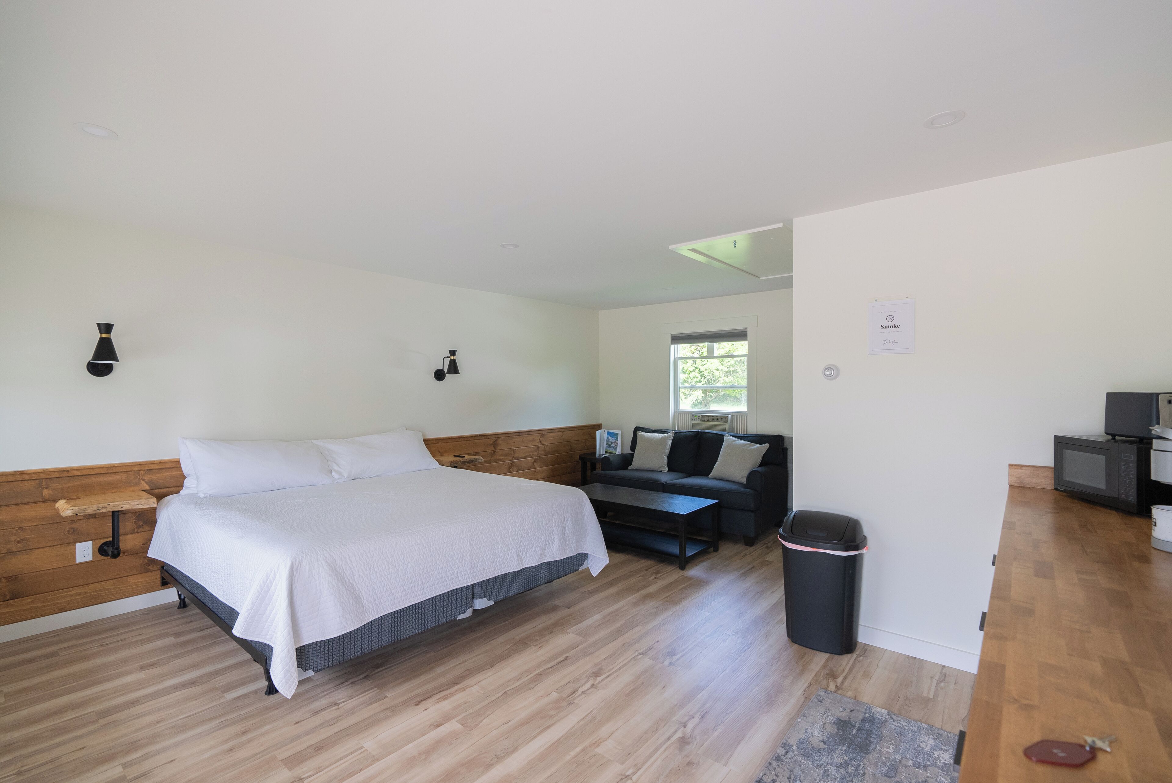 Une chambre à coucher avec un lit en bois, un canapé, une petite table et une poubelle.