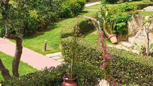A garden with a table and chairs, a pathway, and a building with a view of the sea. - Villa Elias 2BR Lower Apt with Pool (Maleme)