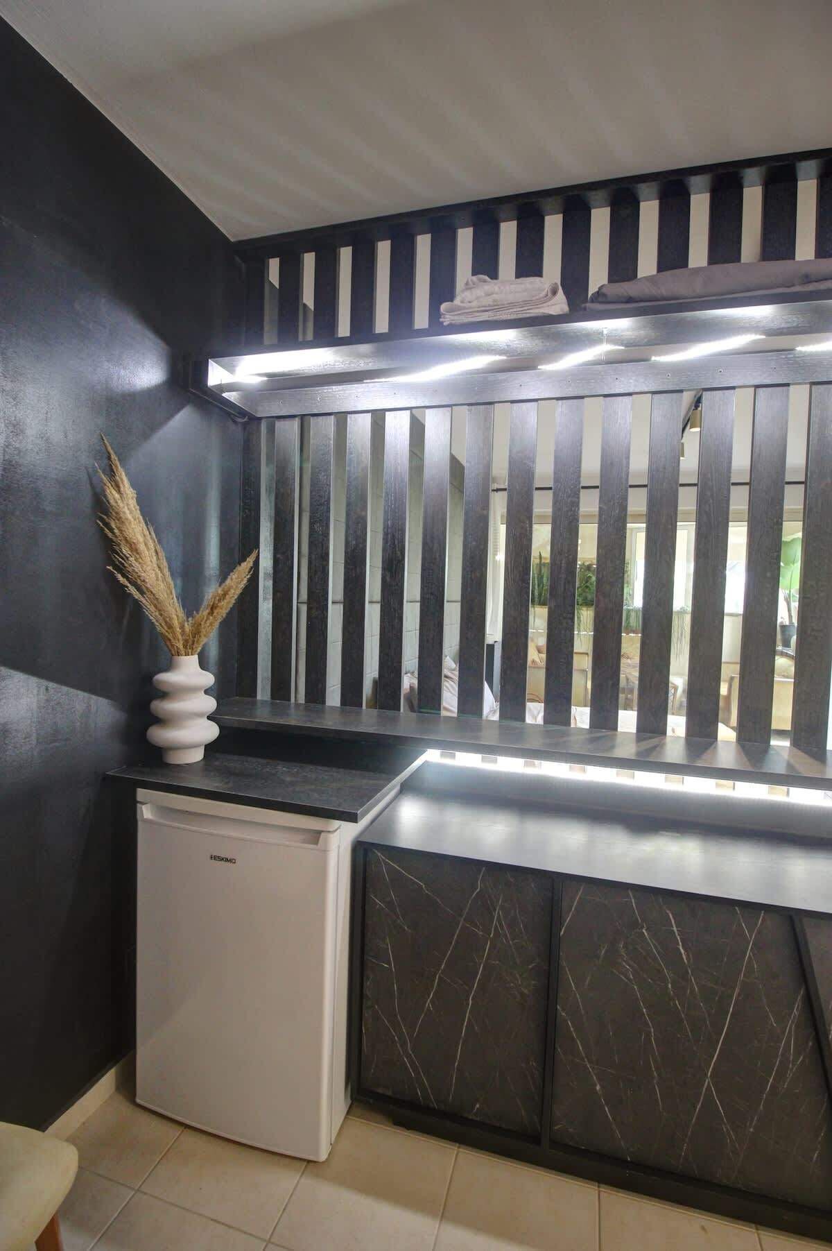 A modern kitchen with a black and white striped backsplash, a built-in stove, and a small refrigerator.