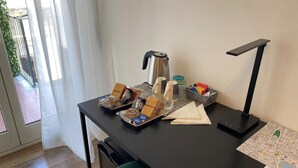 Egy szállodai szoba íróasztallal, kávéfőzővel, asztali lámpával és egy térképpel az asztalon.