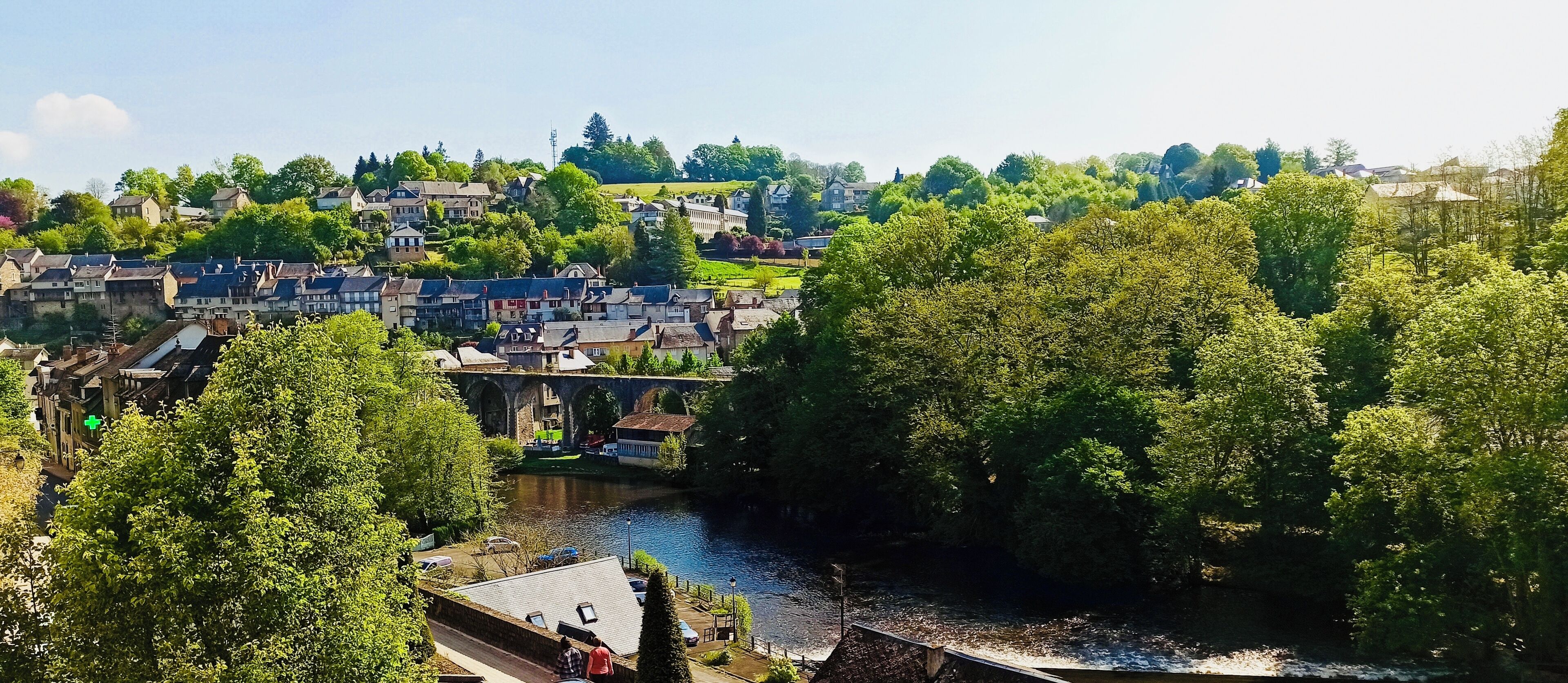 A riverside town with historic buildings, a bridge, and lush greenery.