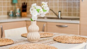 Una cocina con armarios de madera, una mesa blanca con individuales y un jarrón con flores.