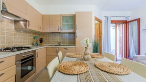 Una cocina moderna con armarios de madera, estufa a gas y comedor con una mesa y un mantel tejido.