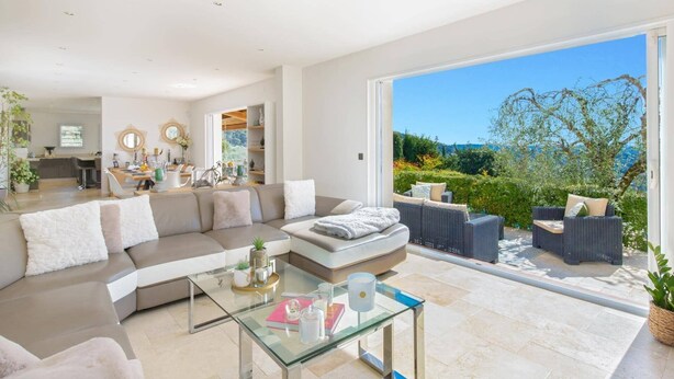 A modern living room with a glass coffee table, a sofa, and wicker furniture.
