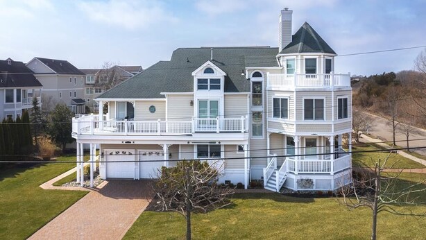 A two-story house with a wrap-around porch, a tower with a balcony, and a garage. - Ocean View Cape May Beach Home w/ Deck | Sleeps 14 (Cape May)