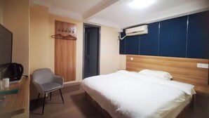 A hotel room with a bed, a chair, a desk with a laptop, and a TV. - Shengshang Hotel (Shanghai)