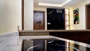 Un hall d’hôtel moderne avec un comptoir d’accueil en marbre, une porte en bois, un mur en marbre noir et une œuvre d’art colorée accrochée au mur.