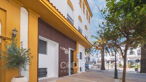 A building with a yellow facade, a sign for 'CORAL ZENITH SUITES', and a visible entrance. - Estudio Triple Semisotano - CORAL ZAHARA Suites by Cadiz4Rentals (Zahara de los Atunes)
