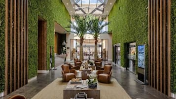 A spacious lobby with a high ceiling, green wall accents, and a central seating area.