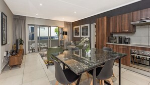 Une cuisine moderne avec des meubles en bois, un four encastré et un coin repas comprenant une table et des chaises en marbre.