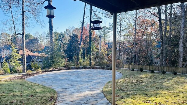 A covered patio area with a curved stone pathway, surrounded by grass and trees. - Private, huge walk-out basement, great location (Marietta)
