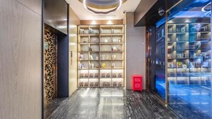 A modern hotel lobby with a marble floor, a central bookshelf, and a glass wall with a cityscape view. - Lishe International Apartment (Shanghai Huaihai Middle Road) (Shanghai)