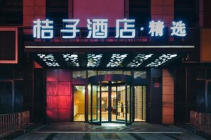 L'ingresso di un hotel con una porta girevole e insegne illuminate.