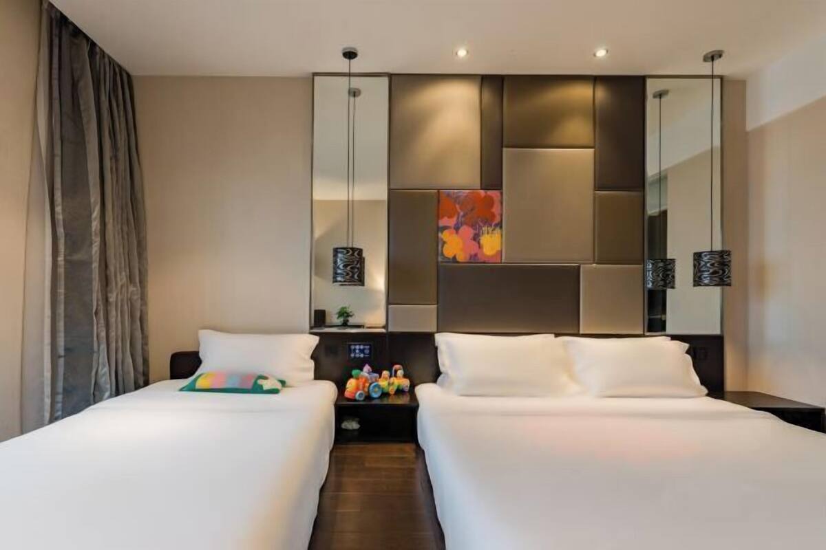 A hotel room with two beds, a large mirror, and a nightstand with decorative items.