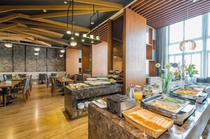 A buffet area with various food options, a seating area with tables and chairs, and a large window providing natural light.
