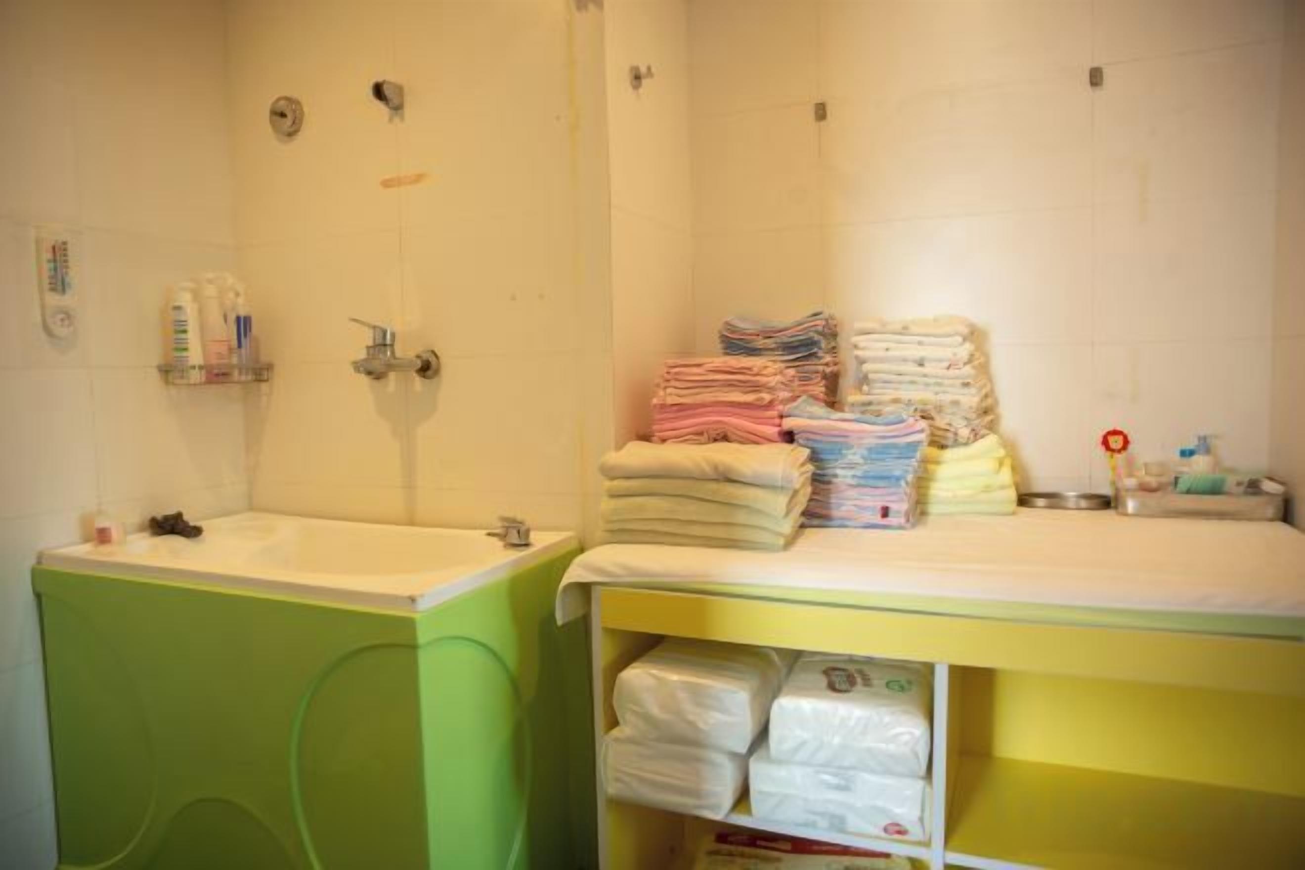 A bathroom with a sink, toilet, and a shelf with towels and toiletries.