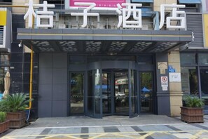 A hotel entrance with a modern design, featuring a curved glass door and a sign above. - Orange Hotel (Wuxi Oufeng Street Huishan Ancient Town Branch) (Wuxi)