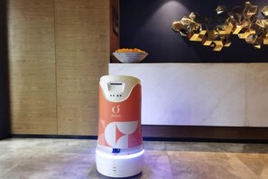 A self-cleaning vacuum cleaner in a modern room with a wooden cabinet and a decorative bowl on the wall. - Orange Hotel (Wuxi Oufeng Street Huishan Ancient Town Branch) (Wuxi)