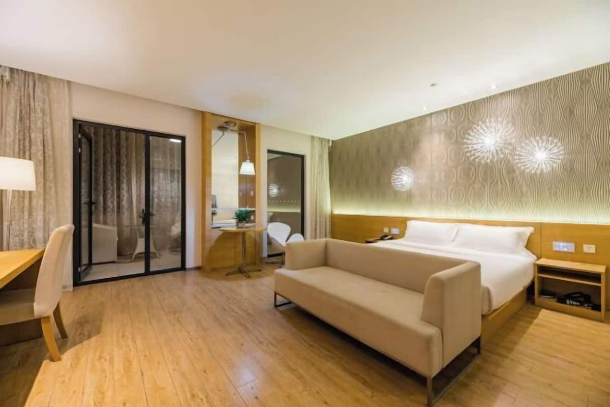 A hotel room with a bed, a sofa, a desk, and a chair.