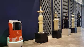 A row of objects on display against a patterned wall, with a modern vehicle-like object on the left.